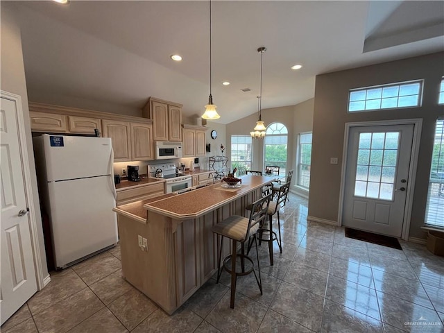 kitchen with a kitchen island, light brown cabinetry, decorative light fixtures, lofted ceiling, and white appliances