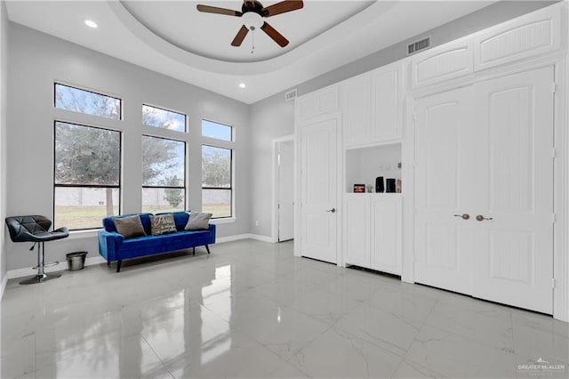 interior space with ceiling fan and a tray ceiling