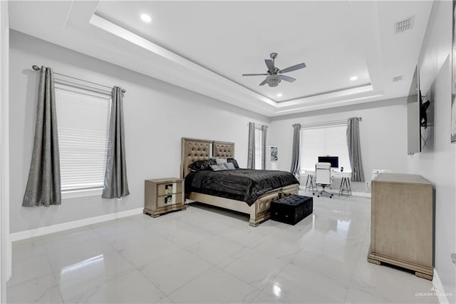 bedroom with ceiling fan and a tray ceiling