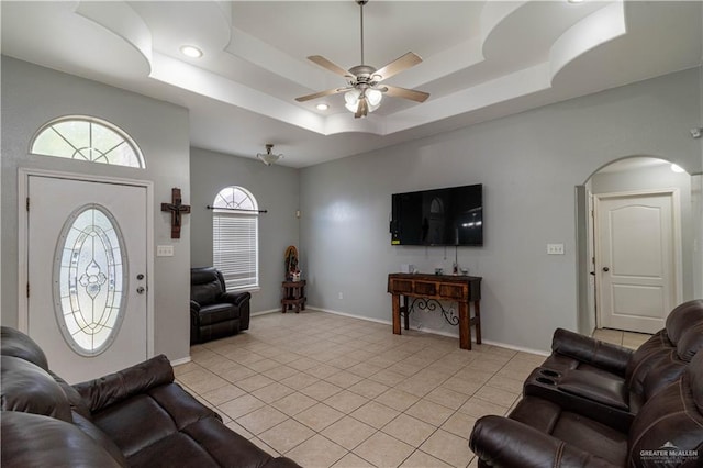 tiled living room featuring ceiling fan and a tray ceiling