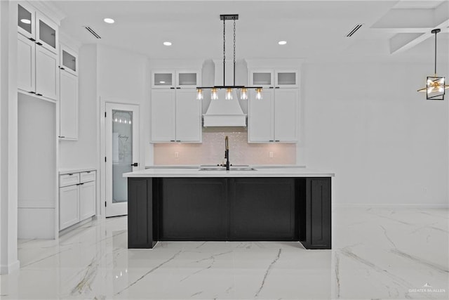 kitchen featuring glass insert cabinets, light countertops, and custom range hood