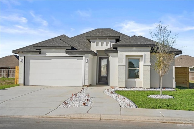 prairie-style home featuring driveway, an attached garage, fence, and stucco siding