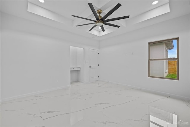 unfurnished room with recessed lighting, marble finish floor, a raised ceiling, and baseboards