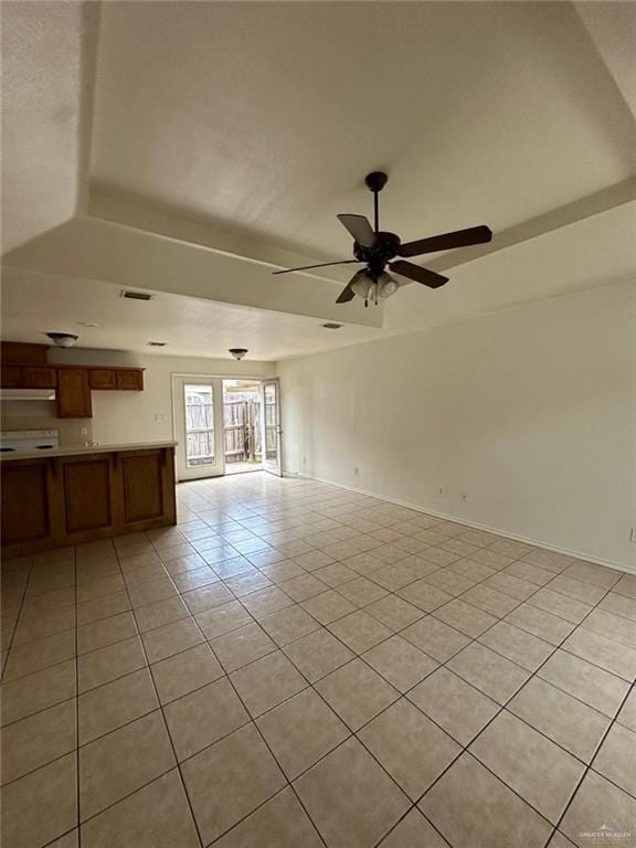 unfurnished living room with light tile patterned floors, ceiling fan, a raised ceiling, and baseboards