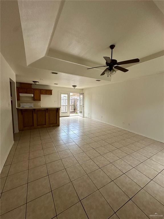 unfurnished living room with baseboards, a tray ceiling, a ceiling fan, and light tile patterned flooring