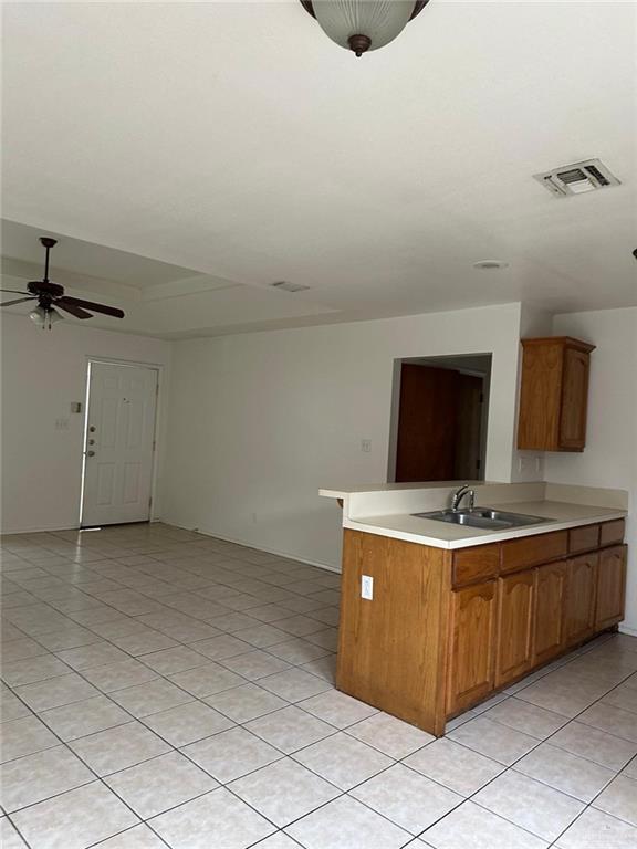 kitchen with open floor plan, light tile patterned floors, light countertops, ceiling fan, and a sink