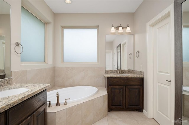 bathroom featuring tiled bath, vanity, and tile patterned flooring