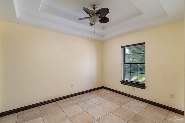 unfurnished room with a raised ceiling, ceiling fan, and light tile patterned floors