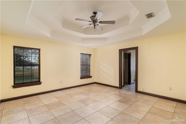 empty room featuring light tile patterned floors, a tray ceiling, and ceiling fan