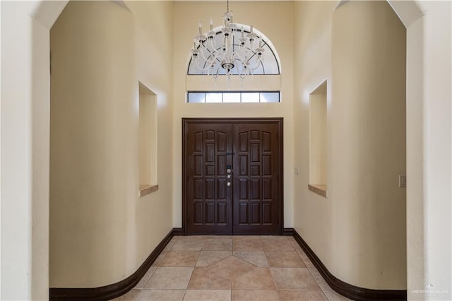 foyer entrance with a high ceiling, an inviting chandelier, and light tile patterned floors