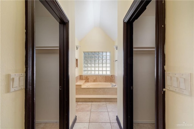 hall featuring light tile patterned floors and lofted ceiling