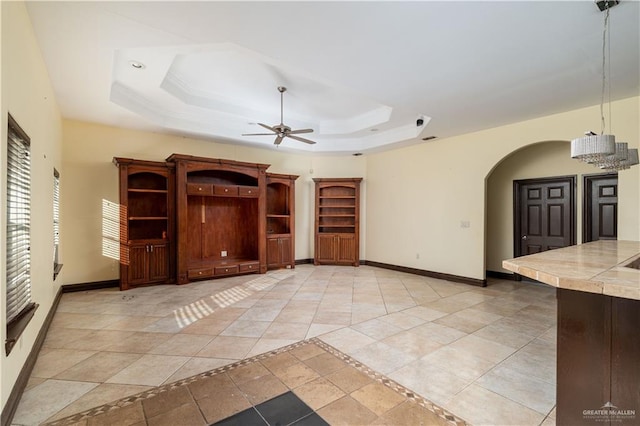 unfurnished living room with a tray ceiling and ceiling fan