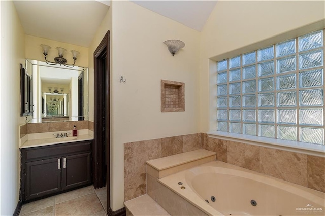 bathroom with tile patterned flooring, vanity, lofted ceiling, and tiled bath