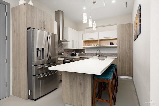 kitchen featuring pendant lighting, backsplash, wall chimney exhaust hood, appliances with stainless steel finishes, and a kitchen island