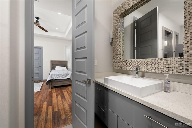 bathroom with hardwood / wood-style flooring, ceiling fan, backsplash, and vanity