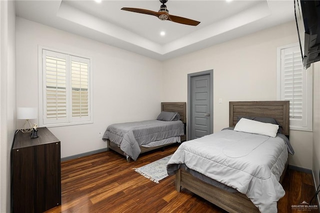 bedroom featuring a raised ceiling, ceiling fan, and dark wood-type flooring