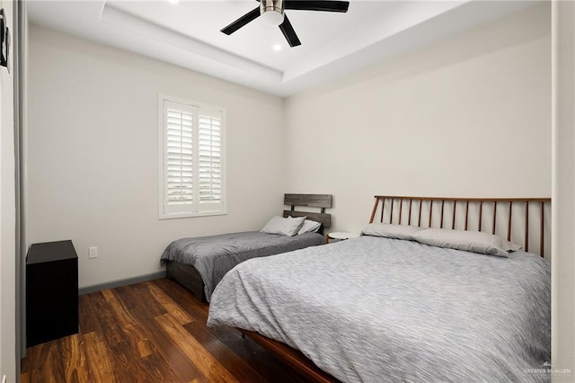 bedroom with a raised ceiling, ceiling fan, and dark hardwood / wood-style flooring