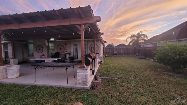 patio terrace at dusk featuring a yard