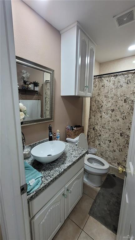 bathroom featuring walk in shower, tile patterned flooring, vanity, and toilet