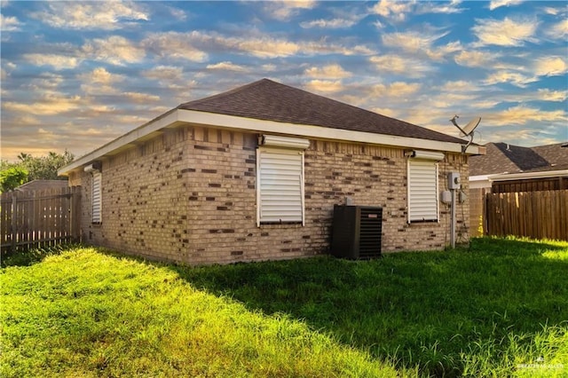 property exterior at dusk featuring central AC and a yard