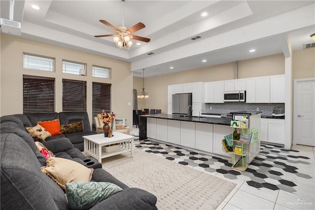 living area featuring visible vents, recessed lighting, a high ceiling, and a tray ceiling