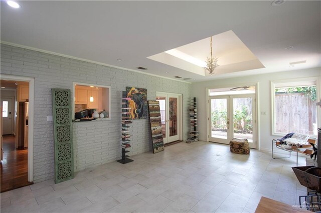 513 S Cynthia St, Mcallen, TX 78501 - living room featuring a tray ceiling, brick wall, ornamental molding, and french doors