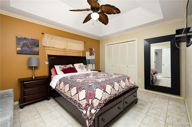 bedroom featuring a raised ceiling, crown molding, ceiling fan, and a closet