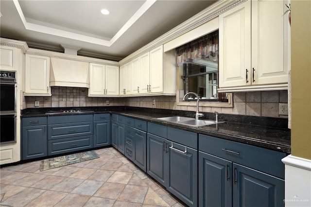 kitchen featuring stainless steel gas stovetop, sink, backsplash, a tray ceiling, and custom range hood