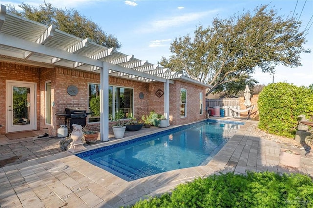 view of swimming pool with a fenced in pool, fence, a patio area, area for grilling, and a pergola