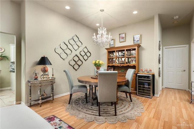 dining space featuring light wood-style flooring, recessed lighting, wine cooler, baseboards, and a chandelier