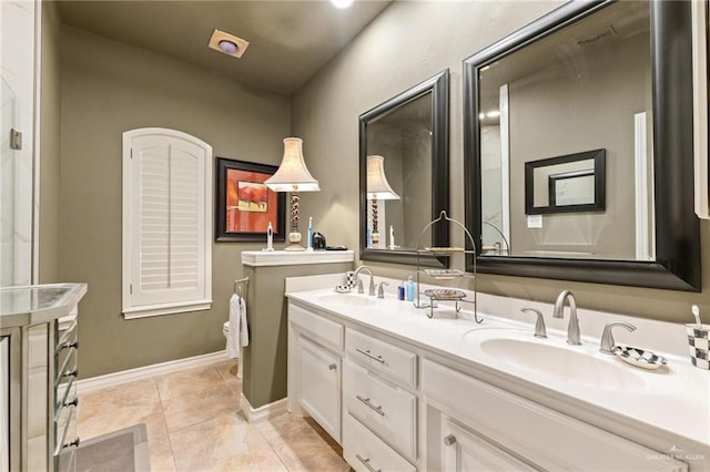 bathroom with a sink, baseboards, double vanity, and tile patterned floors