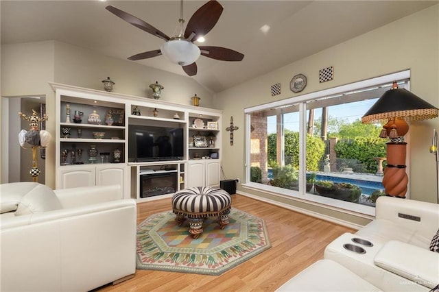 living area featuring a glass covered fireplace, a ceiling fan, light wood-type flooring, and lofted ceiling