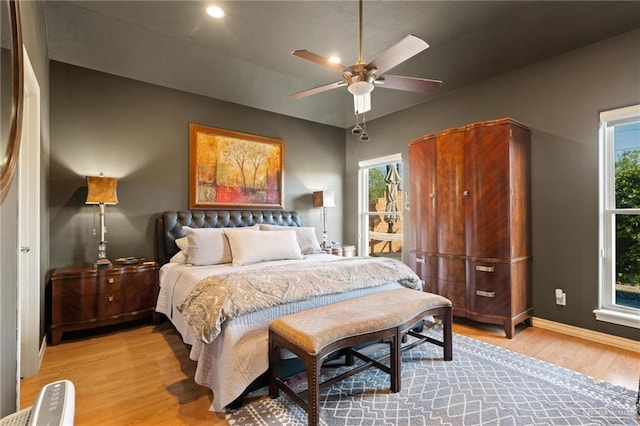 bedroom with vaulted ceiling, multiple windows, light wood-style floors, and baseboards