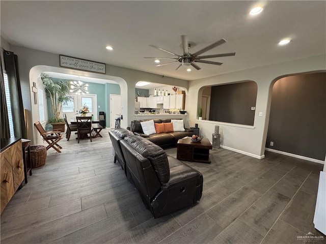 living room with ceiling fan with notable chandelier and dark wood-type flooring