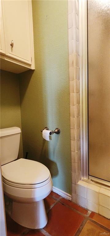 bathroom featuring tile patterned floors, toilet, and a shower