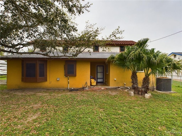 view of front of home with central AC unit, a front lawn, and stucco siding