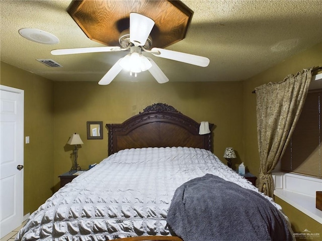 bedroom featuring ceiling fan, visible vents, and a textured ceiling