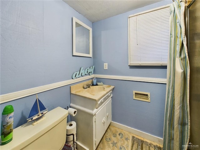 half bathroom with toilet, a wainscoted wall, and vanity