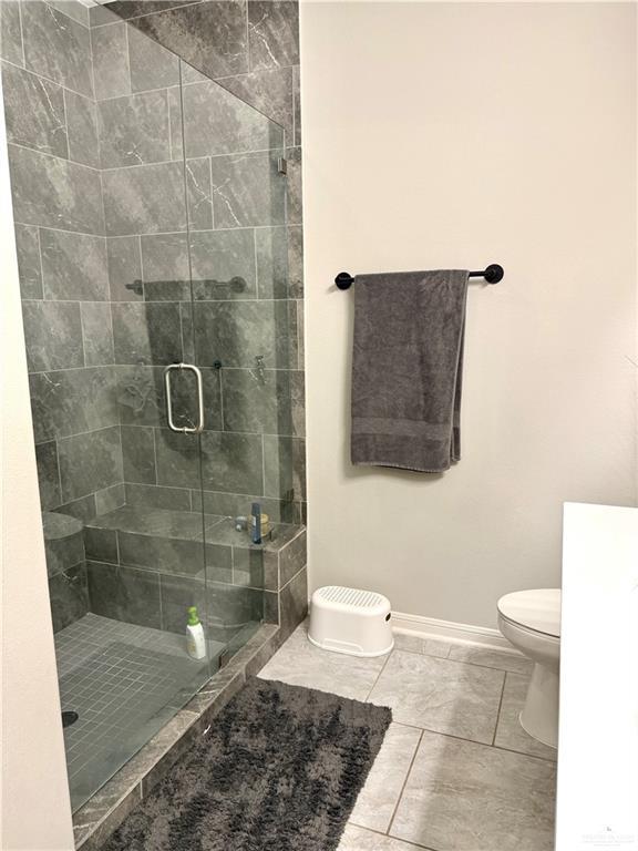 full bathroom featuring toilet, a shower stall, and baseboards