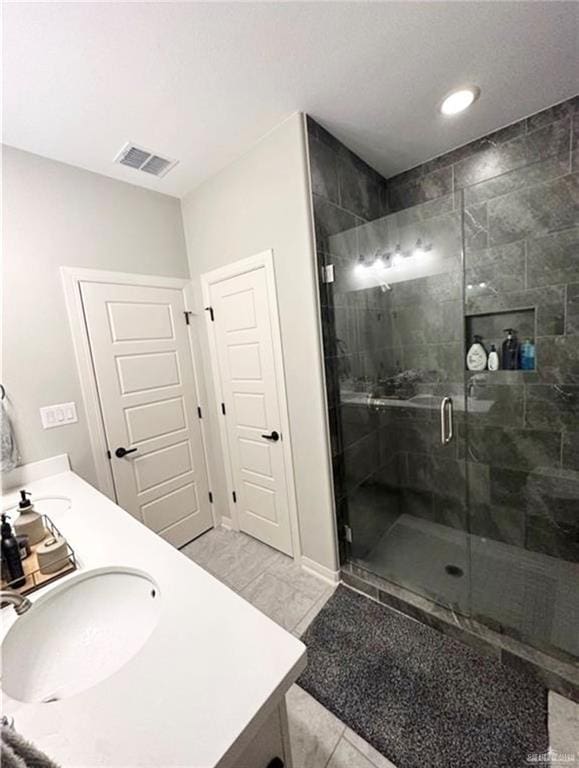 bathroom with double vanity, a sink, visible vents, and a shower stall