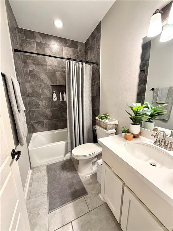 bathroom with toilet, tile patterned flooring, shower / tub combo with curtain, and vanity