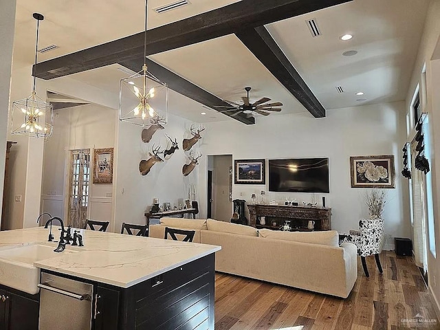 living room with a ceiling fan, beam ceiling, wood finished floors, and visible vents