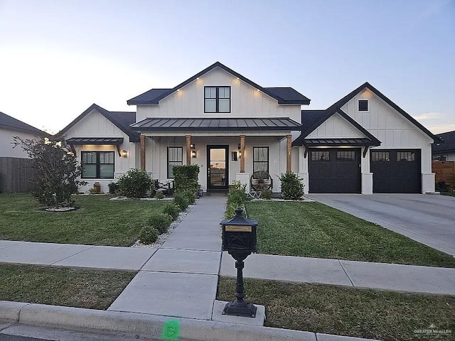 modern inspired farmhouse with a front yard, driveway, a standing seam roof, an attached garage, and board and batten siding