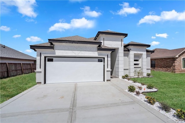 prairie-style house with a garage, concrete driveway, fence, and a front yard