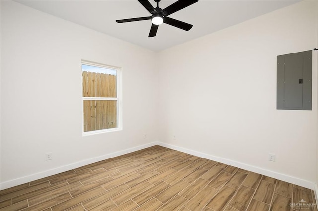 spare room featuring electric panel, baseboards, and light wood-style floors