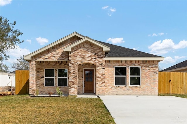 view of front facade featuring fence, brick siding, and a front yard