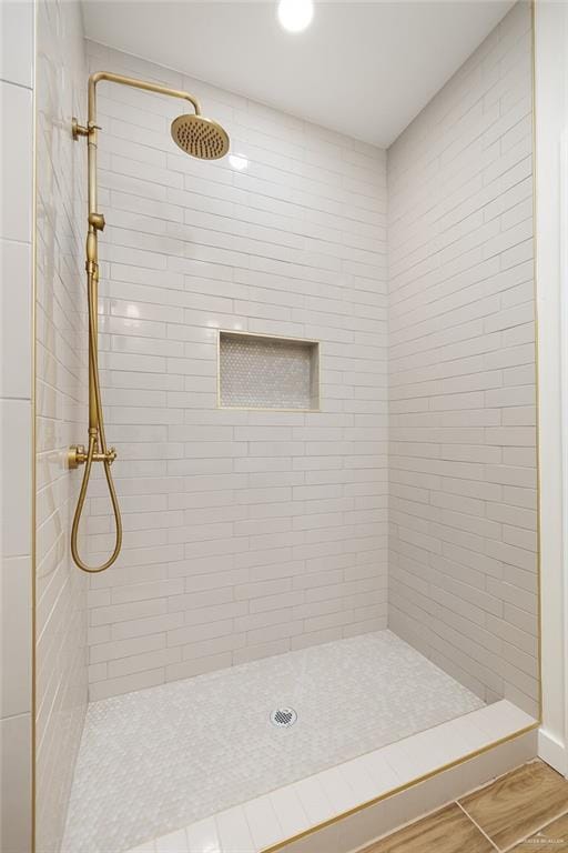 full bath with a tile shower and wood finished floors