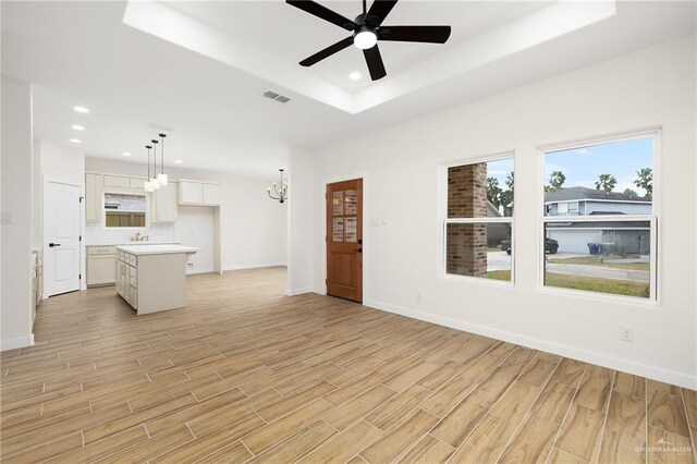 unfurnished living room featuring recessed lighting, light wood-style floors, and ceiling fan with notable chandelier