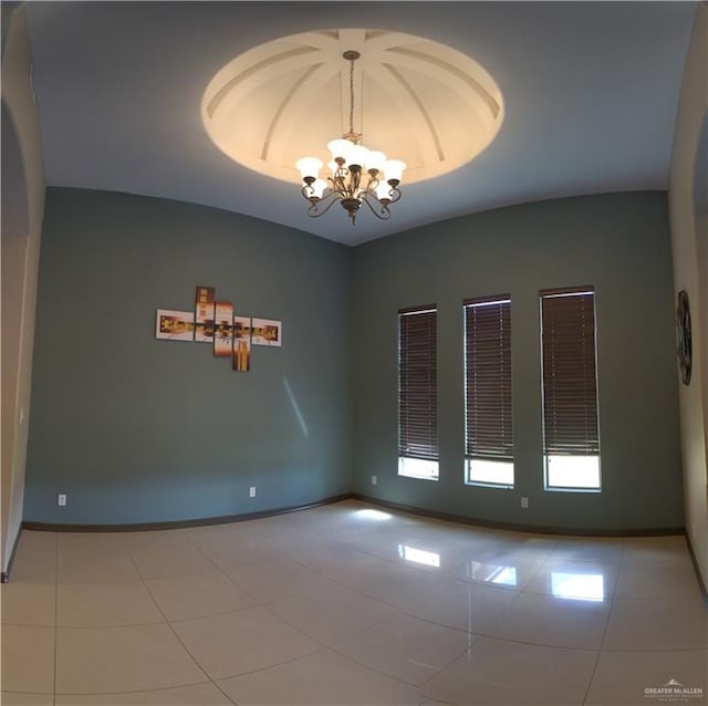 tiled empty room with a chandelier