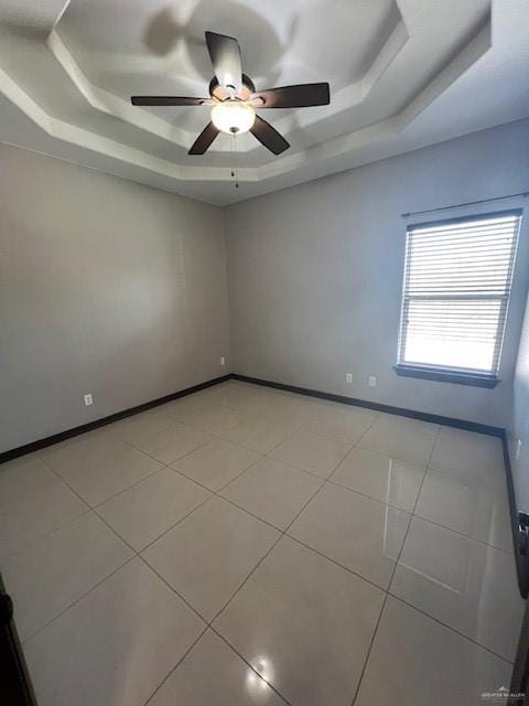 tiled spare room with a raised ceiling and ceiling fan